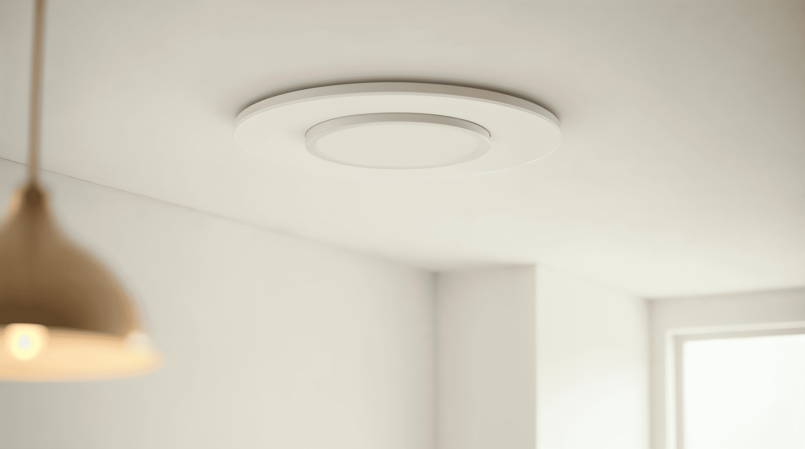Bouche d’extraction VMC blanche au plafond d’une salle de bain moderne, lumière naturelle douce et plafond mat